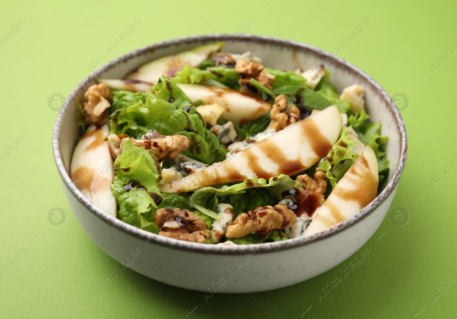 Photo of Delicious pear salad with sauce in bowl on green background, closeup