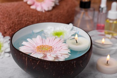 Photo of Beautiful composition with bowl of water, flowers and candles on light table, closeup. Spa treatment