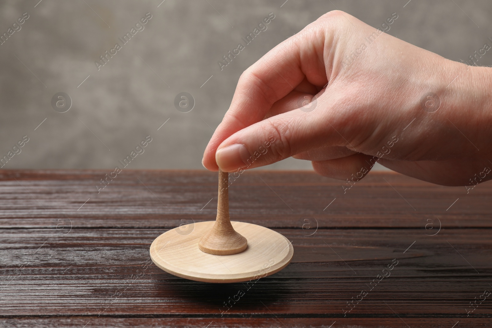 Photo of Woman playing with spinning top at wooden table, closeup