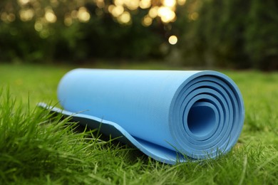 Photo of Bright karemat or fitness mat on fresh green grass outdoors