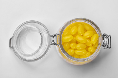 Photo of Tasty small lemon drops in glass jar isolated on white, top view