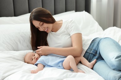 Mother with her cute baby on bed indoors