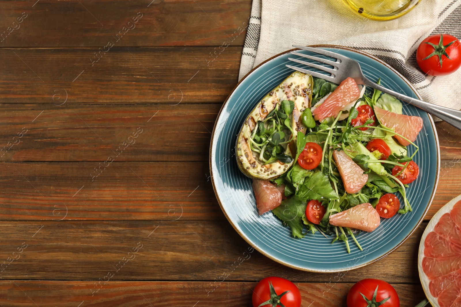 Photo of Delicious pomelo salad with grilled avocado served on wooden table, flat lay. Space for text