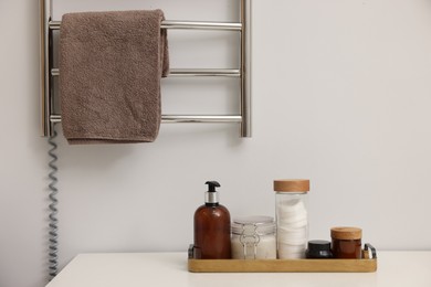 Photo of Stylish bathroom interior with heated towel rail and cosmetic products