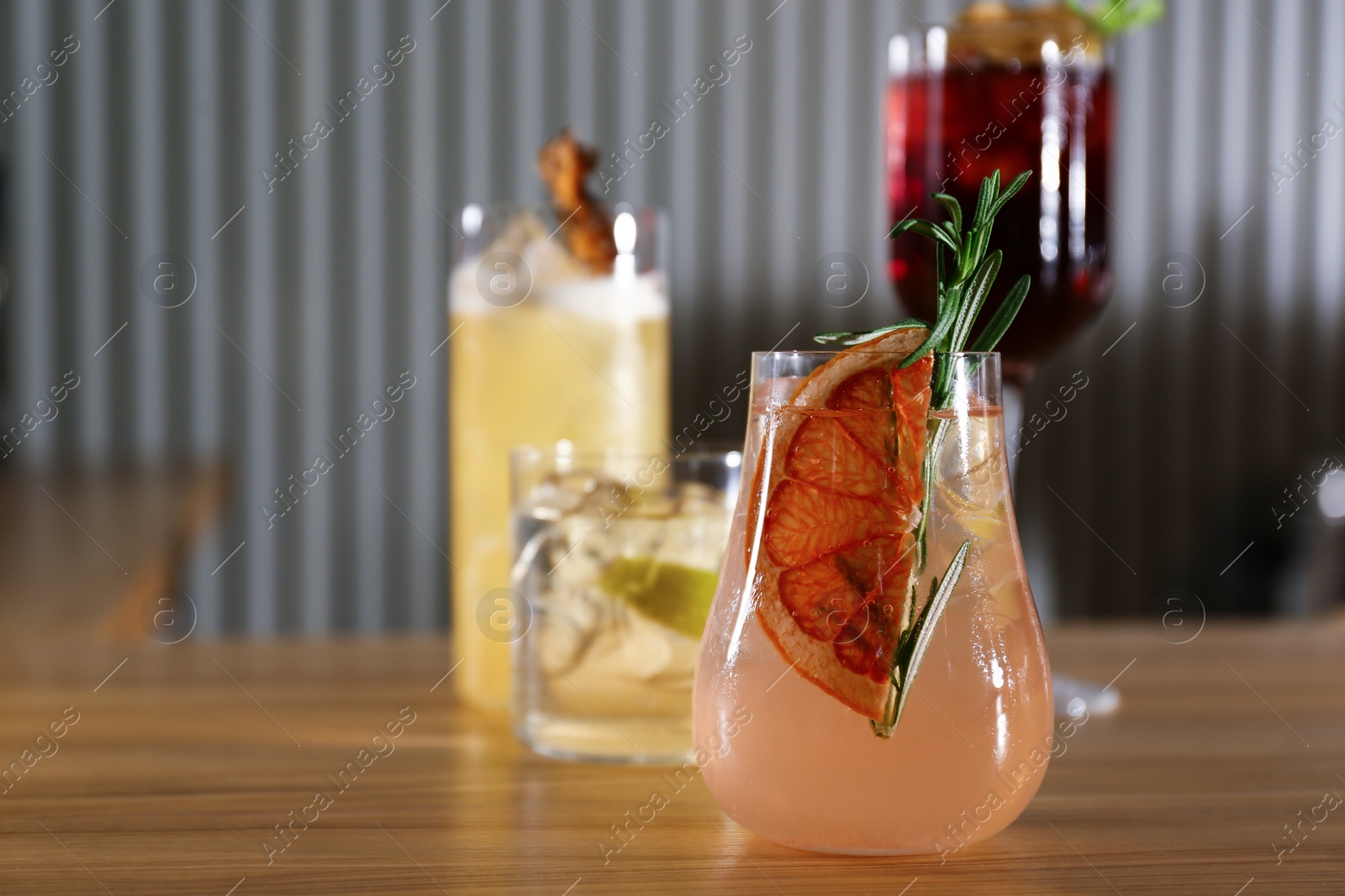 Photo of Glasses of delicious cocktails with vodka on wooden counter in bar