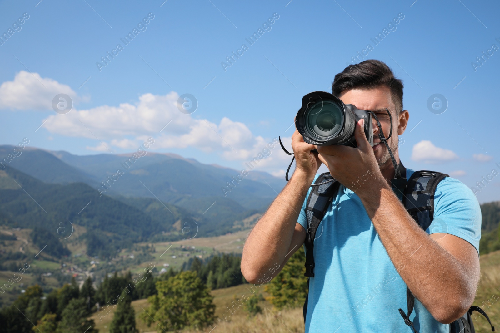 Photo of Professional photographer taking picture with modern camera in mountains. Space for text