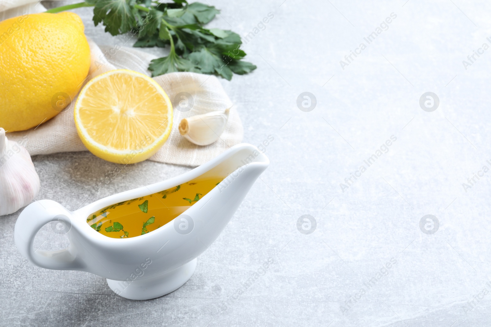 Photo of Ceramic boat with lemon sauce on light table, space for text. Delicious salad dressing