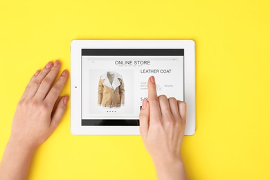 Woman with tablet shopping online on yellow background, top view