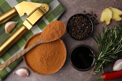 Aromatic spices, fresh ingredients for marinade and garlic press on brown table, flat lay