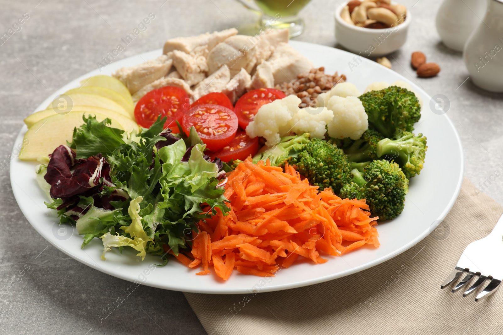 Photo of Balanced diet and healthy foods. Plate with different delicious products on grey table, closeup