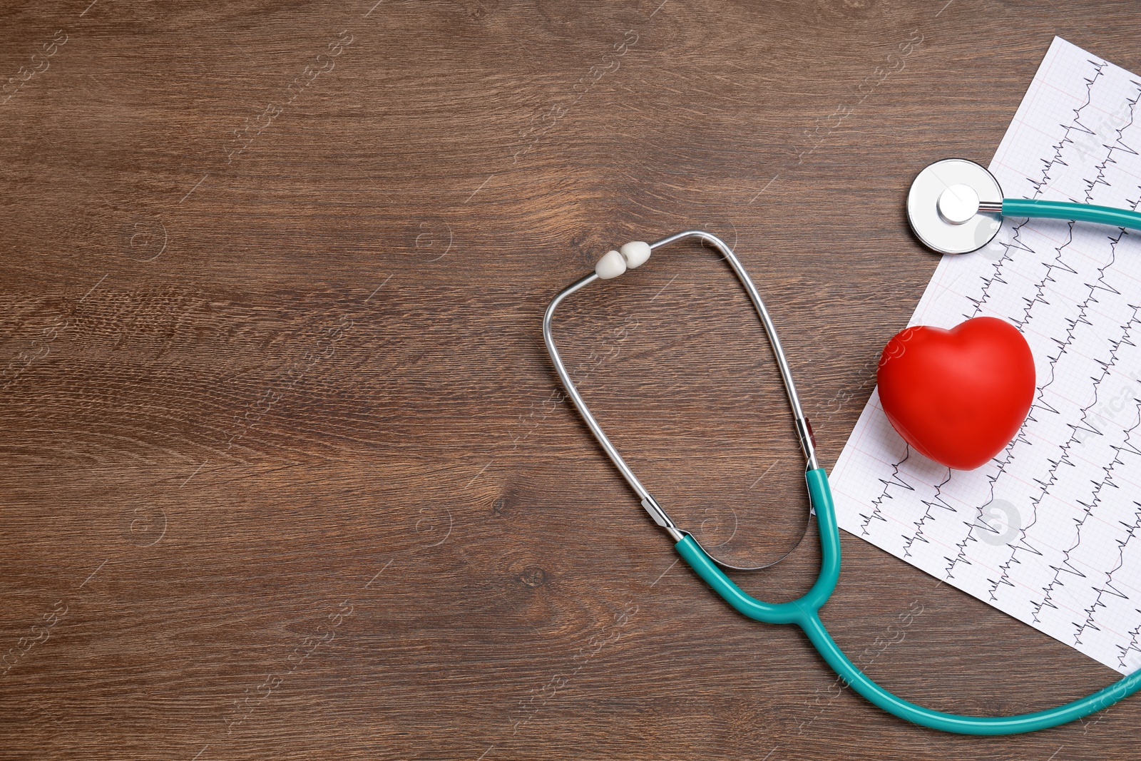 Photo of Stethoscope, cardiogram, red decorative heart and space for text on wooden background, flat lay. Cardiology concept