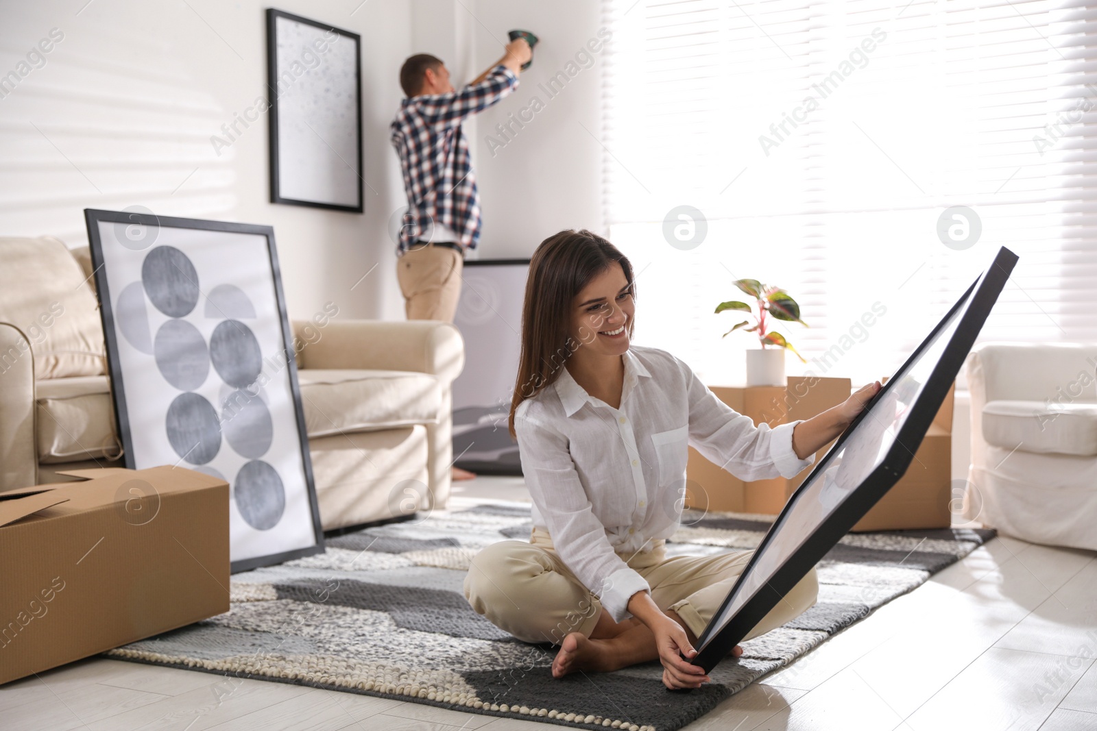 Photo of Happy couple decorating room with pictures together. Interior design