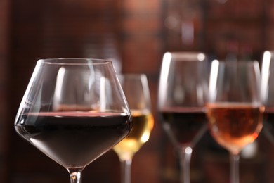 Photo of Tasty red wine in glass against blurred background, space for text
