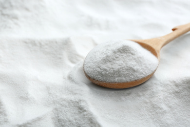 Photo of Wooden spoon on baking soda, closeup view