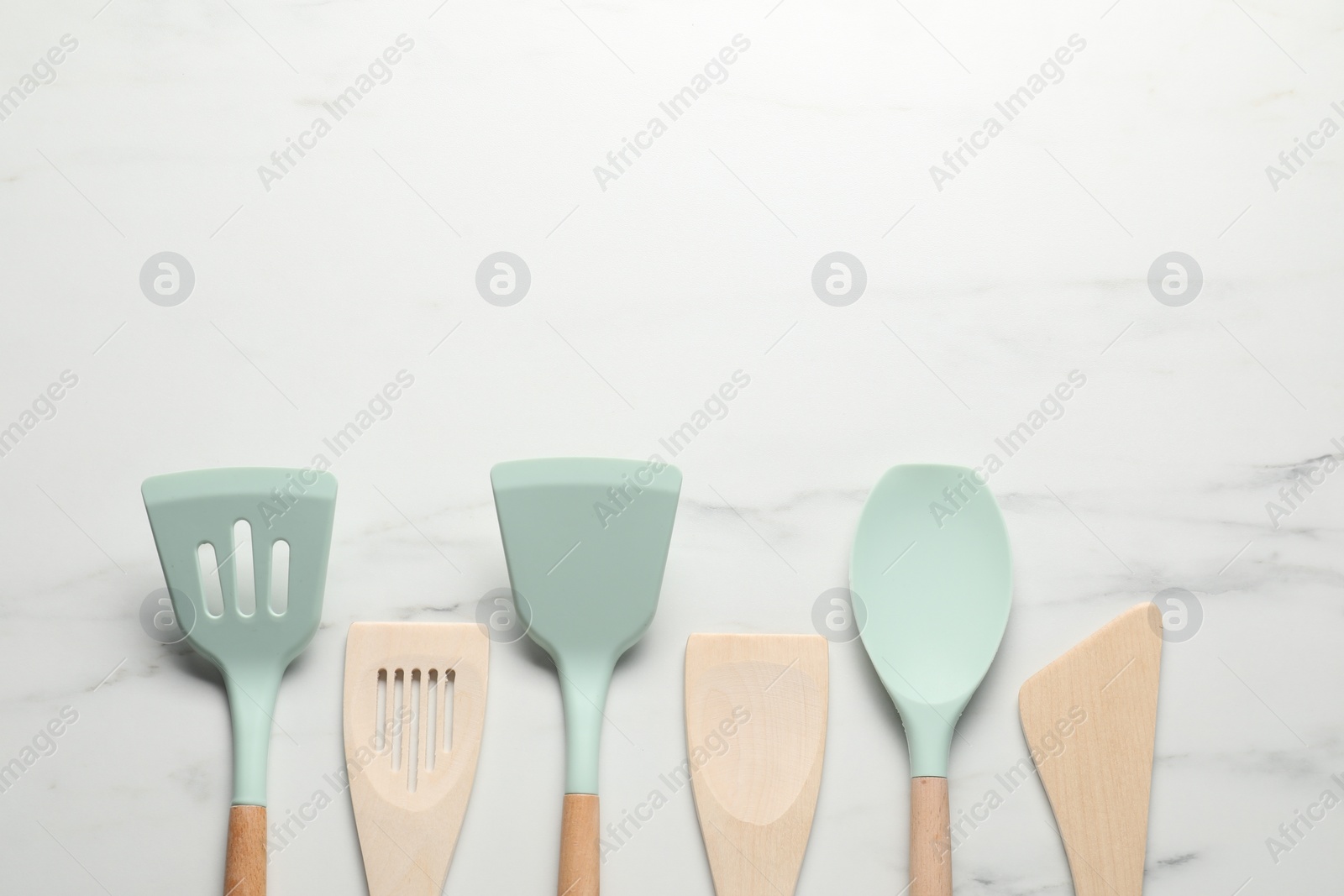 Photo of Different spatulas on white marble table, flat lay. Space for text