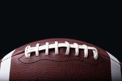 Photo of Leather American football ball on black background, closeup