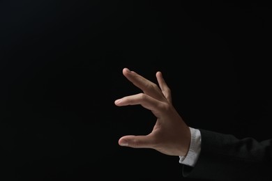 Photo of Man holding something in hand on black background, closeup. Space for text