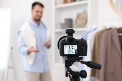 Fashion blogger showing clothes while recording video at home, focus on camera