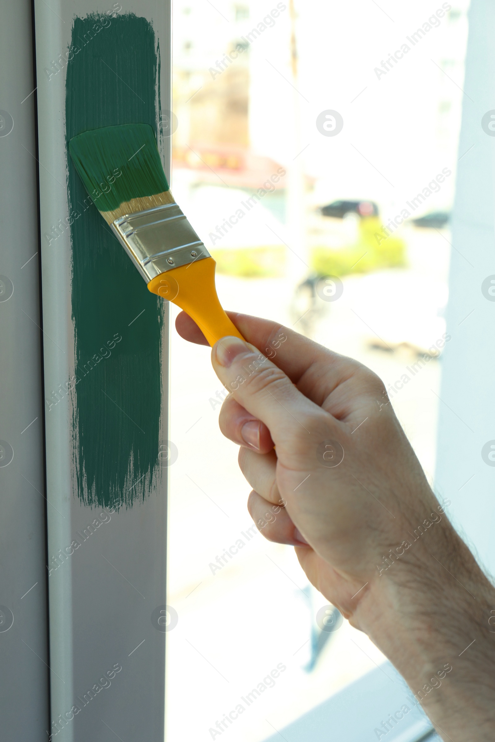 Image of Man painting window frame at home, closeup