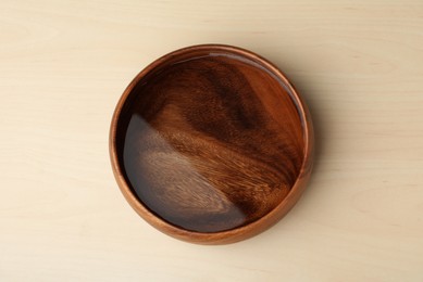 Photo of Bowl full of water on wooden table, top view