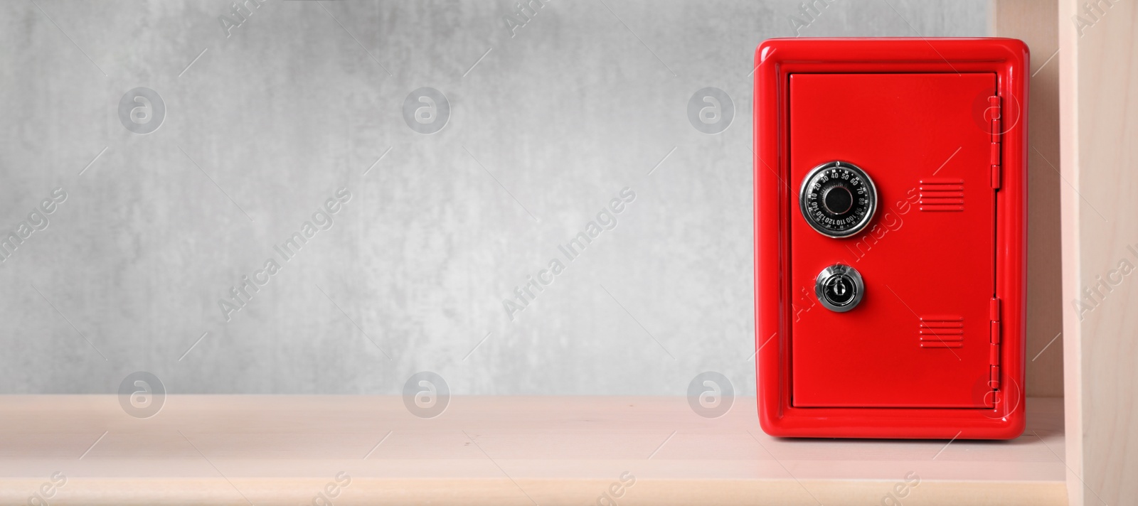 Image of Red steel safe with mechanical combination lock on shelf, banner design. Space for text