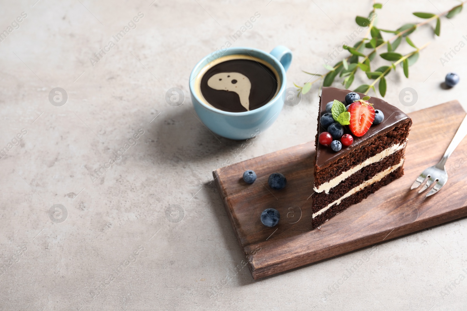 Photo of Wooden board with chocolate sponge berry cake and cup of coffee on grey background