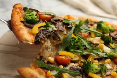 Photo of Taking piece of delicious vegetarian pizza at table, closeup