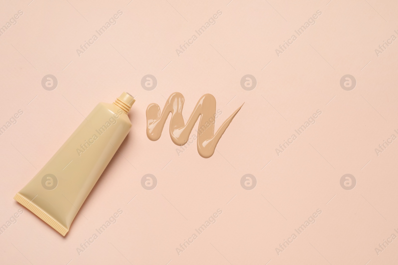 Photo of Liquid foundation and swatch on beige background, top view. Space for text