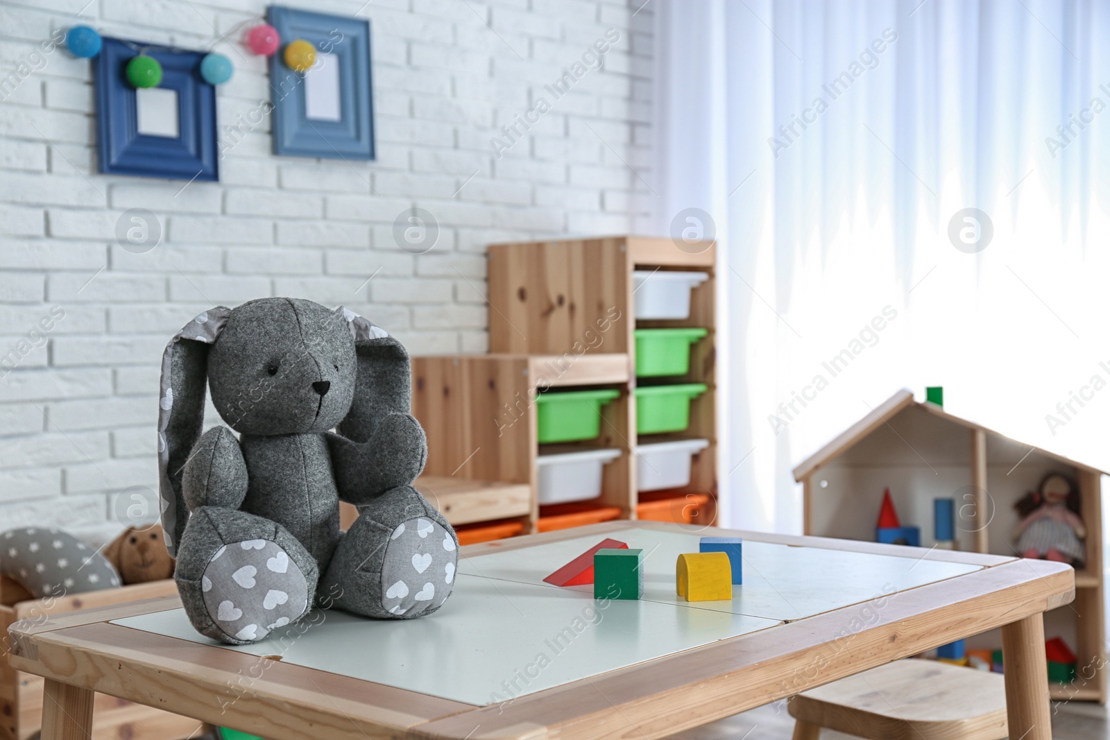 Photo of Stuffed rabbit on table in child room interior