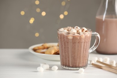 Photo of Cup of aromatic hot chocolate with marshmallows and cocoa powder on white table, closeup. Space for text
