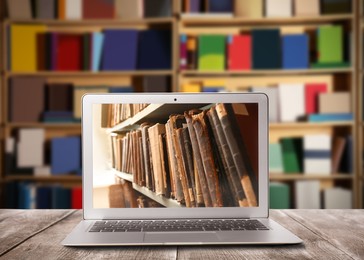 Image of Online library. Modern laptop on wooden table and shelves with books indoors