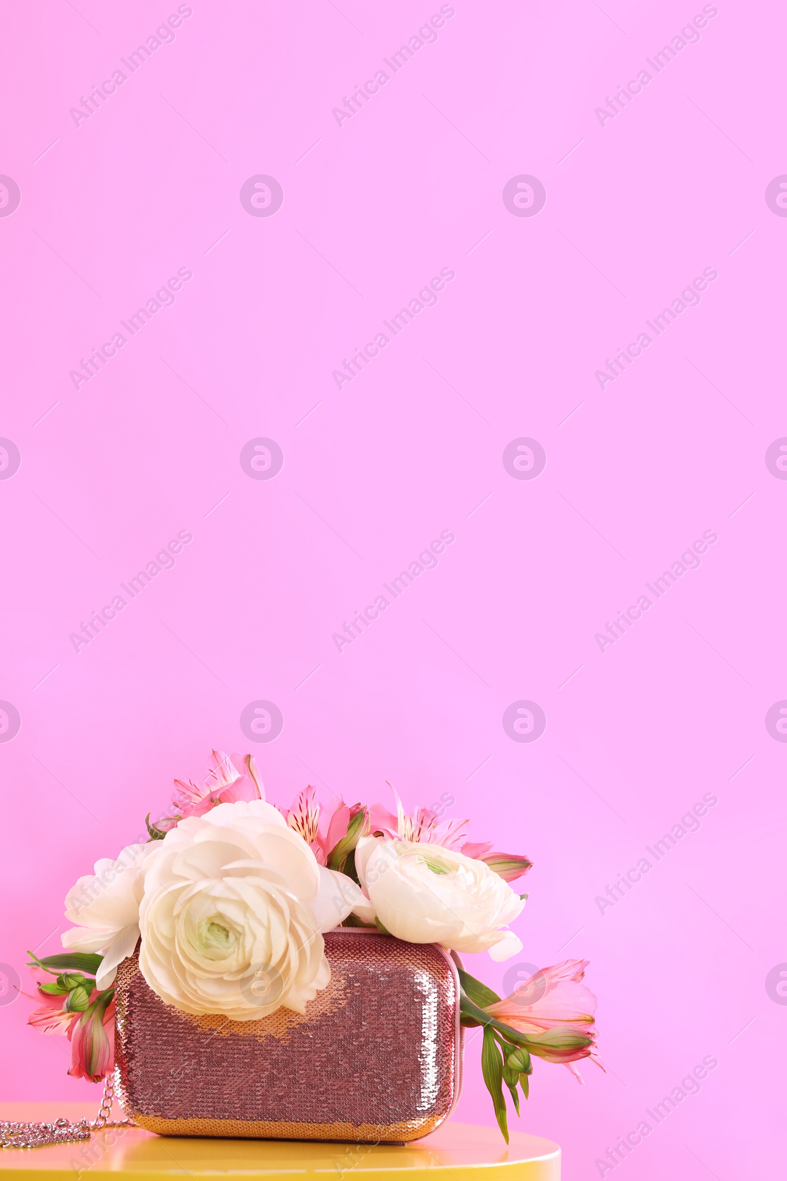 Photo of Elegant handbag with spring flowers on table against pink background, space for text