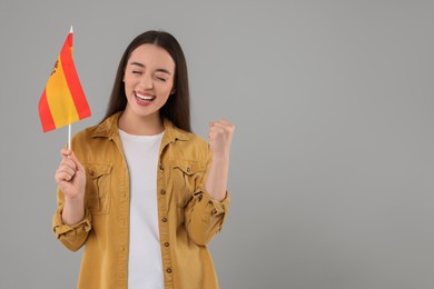 Photo of Emotional young woman holding flag of Spain on light grey background, space for text