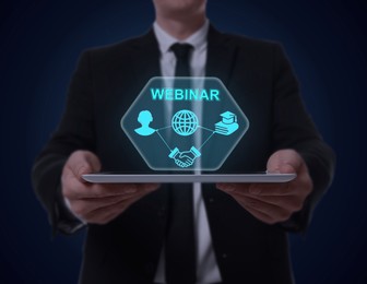 Webinar. Man holding tablet on dark blue background, closeup. Virtual screen with icons over computer