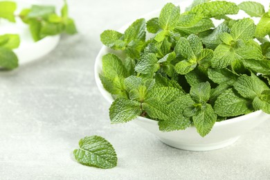 Photo of Bowl with fresh green mint leaves on grey table. Space for text