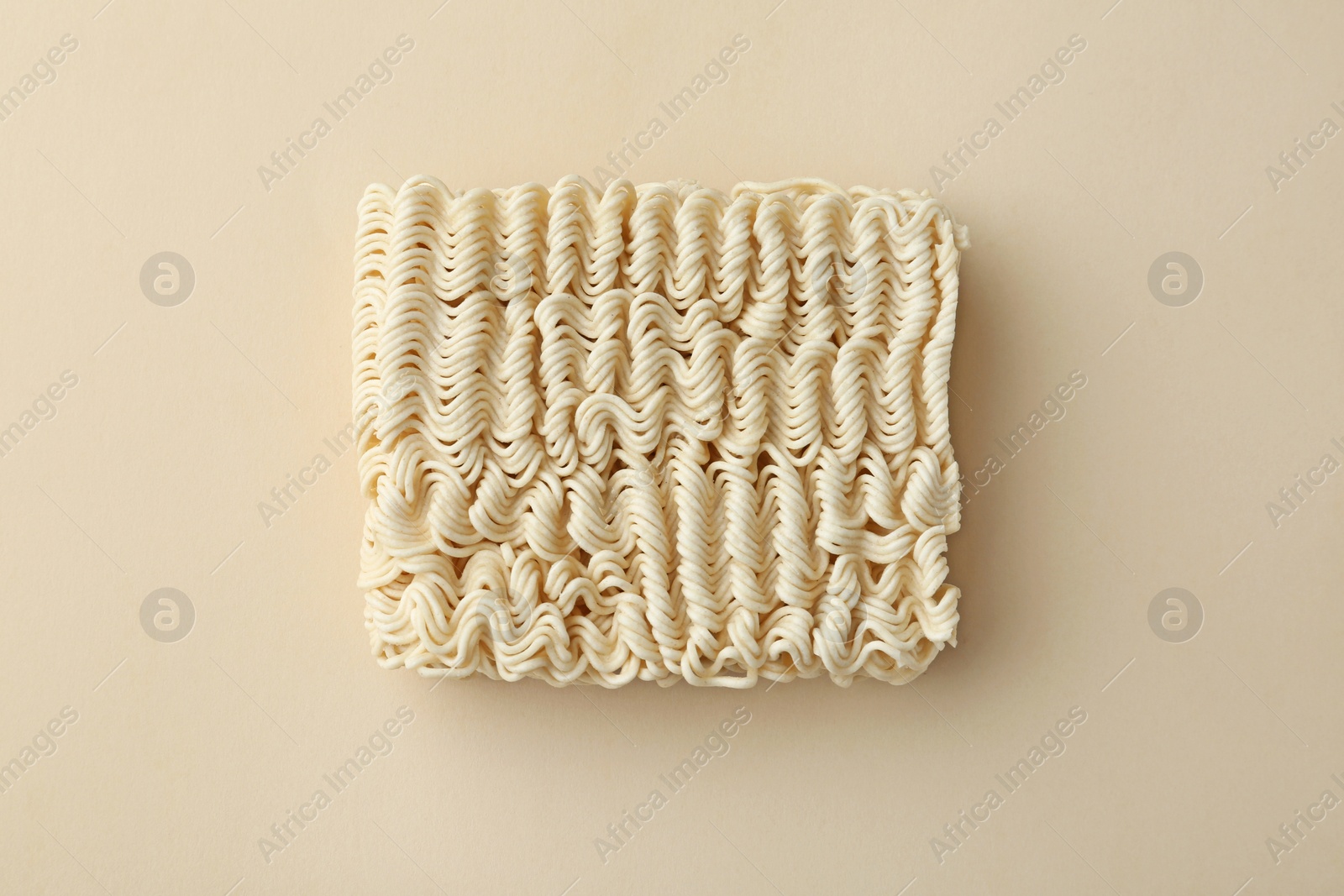 Photo of Block of quick cooking noodles on color background, top view