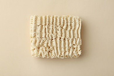 Block of quick cooking noodles on color background, top view