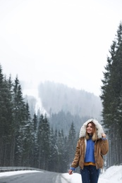 Photo of Young woman walking near snowy forest. Winter vacation