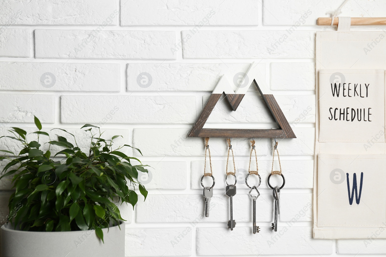 Photo of Wooden key holder on white brick wall indoors