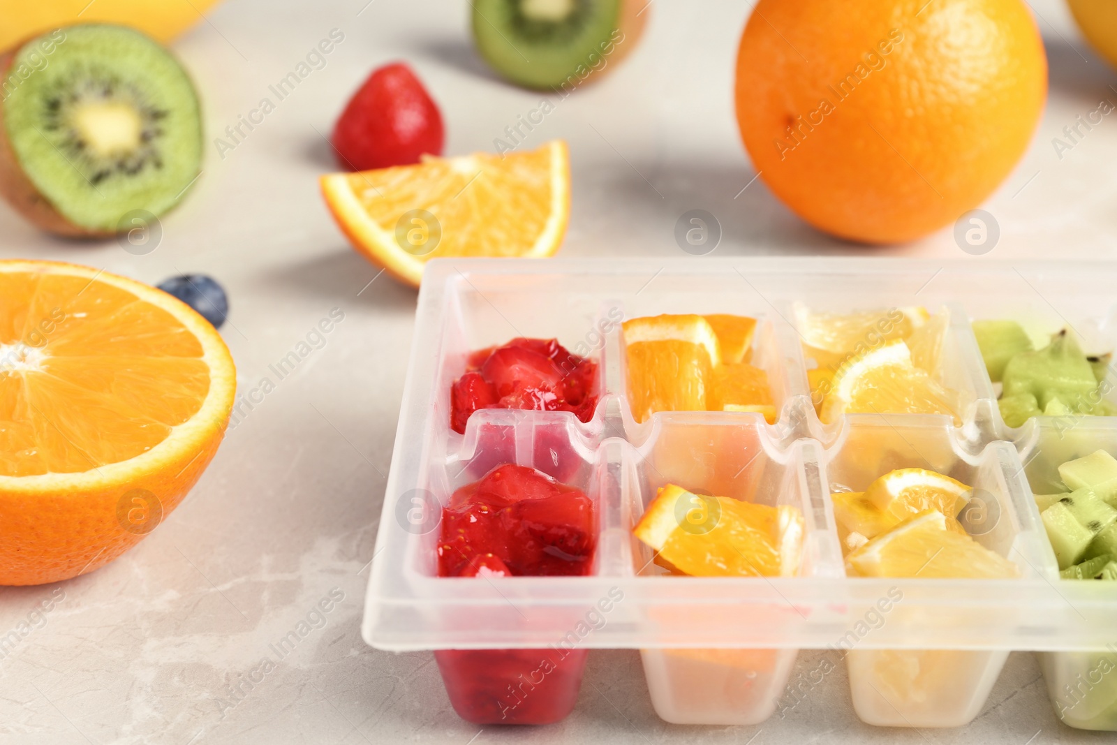 Photo of Ice cube tray with different fruits and berries on table, closeup