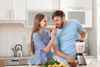 Photo of Cute young couple preparing delicious milk shake in kitchen