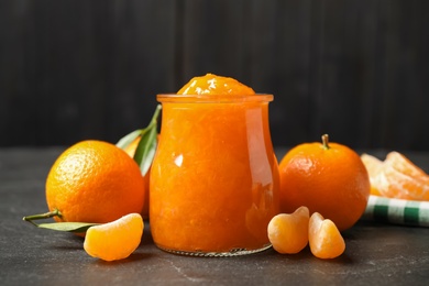 Photo of Composition with tasty tangerine jam on dark table