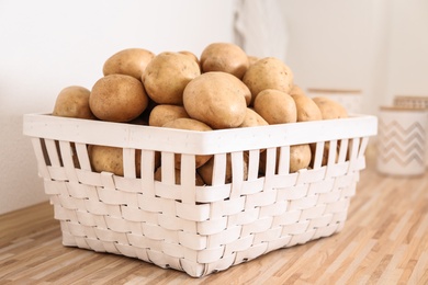 Photo of Basket with potatoes on wooden kitchen counter. Orderly storage