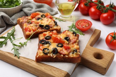 Photo of Tasty pizza toasts and ingredients on white table