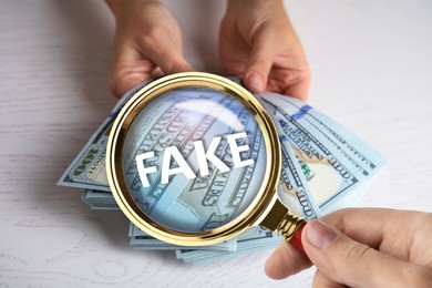 Image of Woman with magnifying glass detecting fake money, closeup