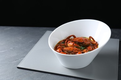 Photo of Delicious boiled crabs with sauce on grey table, space for text