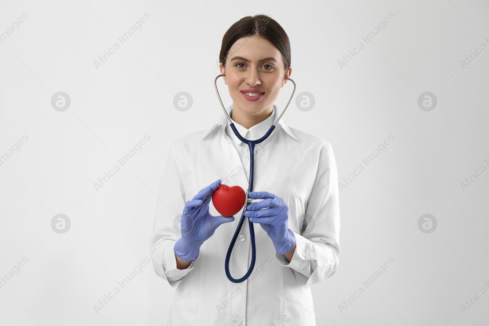 Photo of Doctor with stethoscope and red heart on white background. Cardiology concept