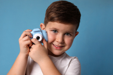 Photo of Little photographer with toy camera on light blue background