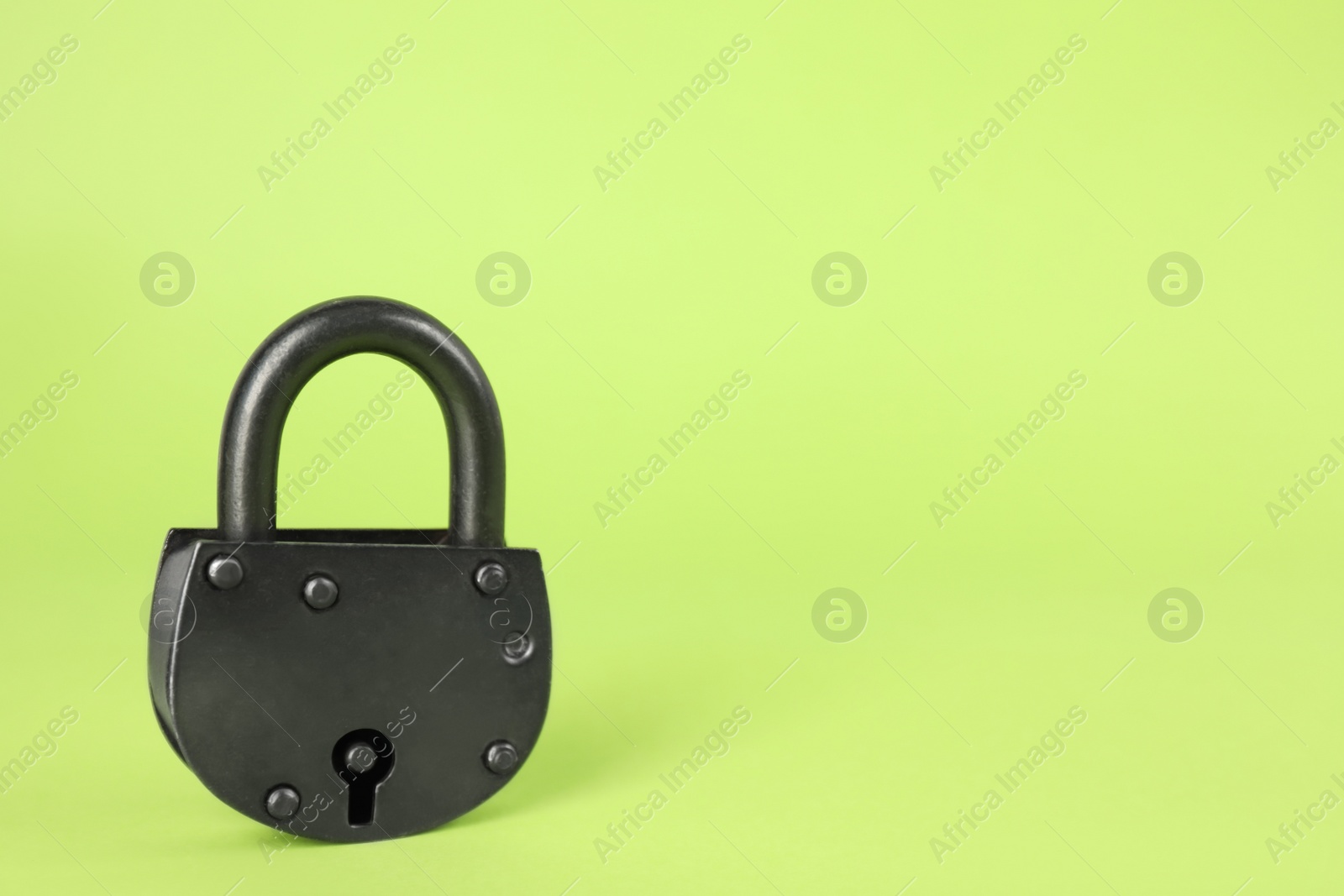Photo of Vintage padlock on light green background. Space for text