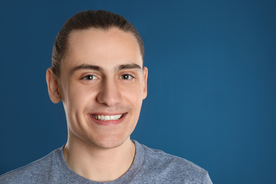 Portrait of happy young man on blue background, space for text